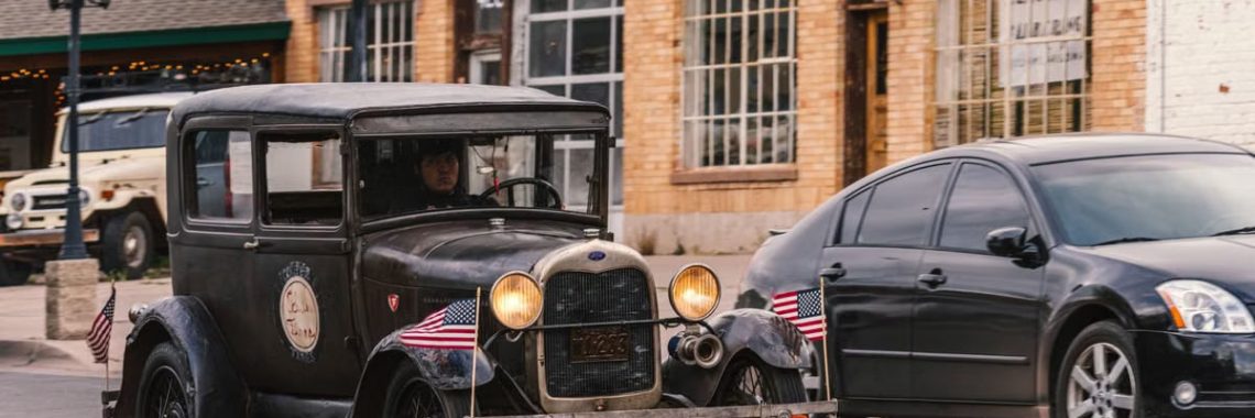 Vintage Ford with American flags driving on historic Route 66 in Williams, Arizona.