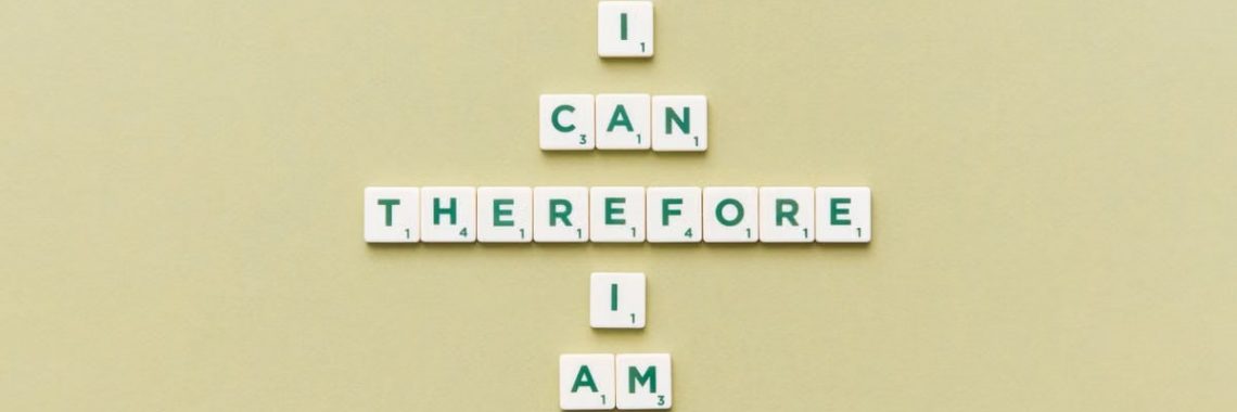 Inspirational phrase 'I Can Therefore I Am' arranged using Scrabble tiles on a green background.